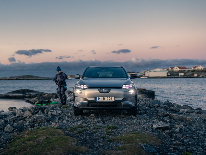 Subaru Solterra akmenuotoje pakrantėje su žmogumi, vilkinčiu nardymo įrangą.